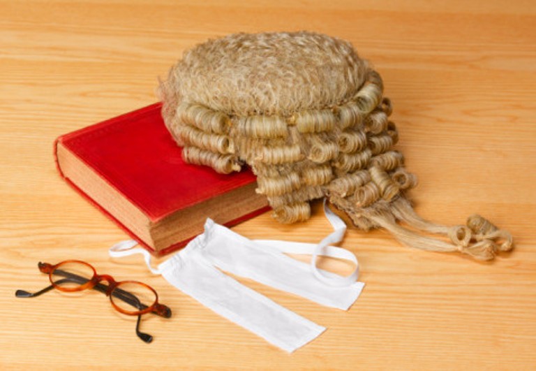 Barristers wig on legal book beside spectacles