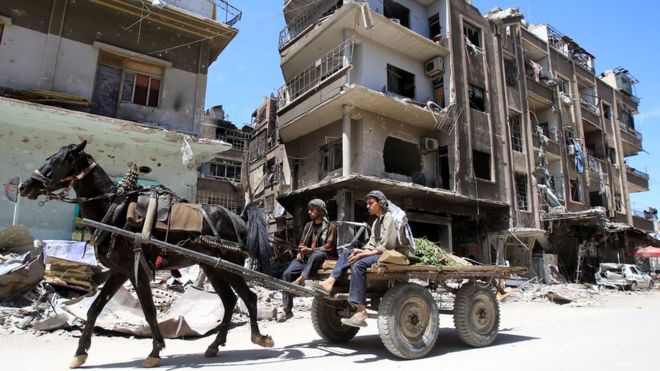 Residents ride through the ruined streets of Douma on Sunday, a week after the attack