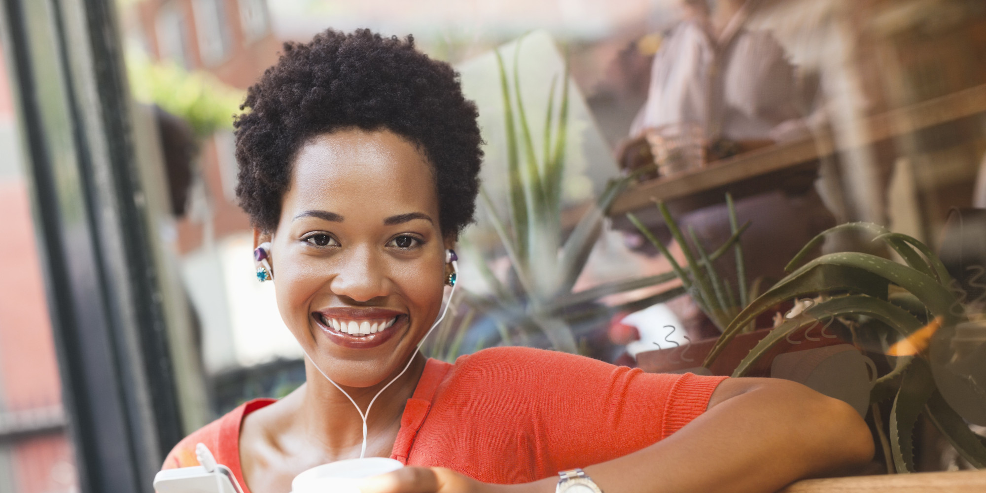 Woman listening to earphones by coffee shop