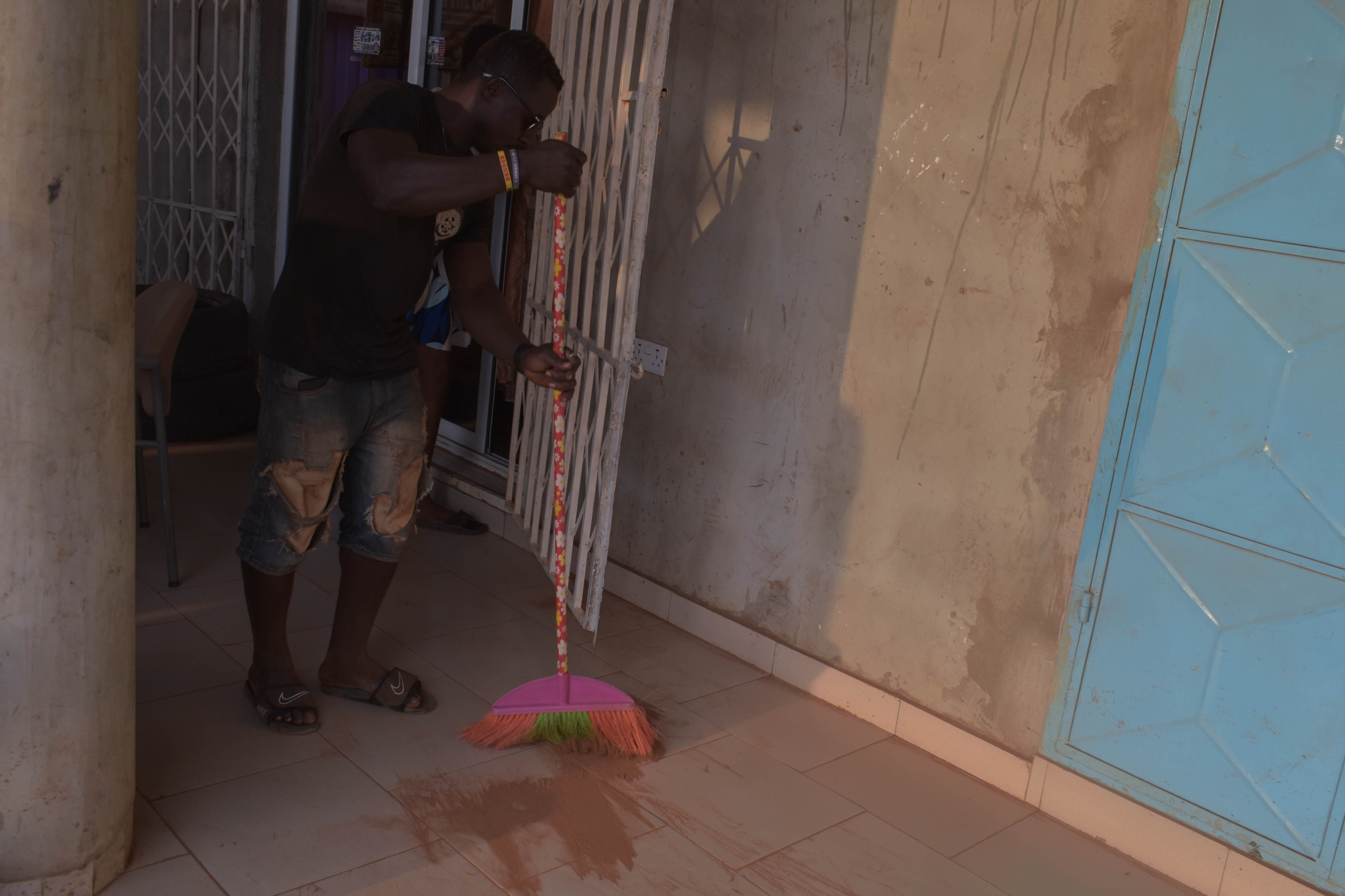Kojo Baah does some sweeping to clear some of the dust from the shop