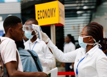 FILE PHOTO: A health worker checks the temperature of a traveller as part of the coronavirus screening procedure at the Kotoka International Airport in Accra, Ghana January 30, 2020. REUTERS/Francis Kokoroko/File Photo - RC2EUE9X5YKK