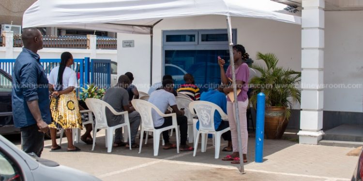Persons wait outside a bank to comply with the new public gathering advisories