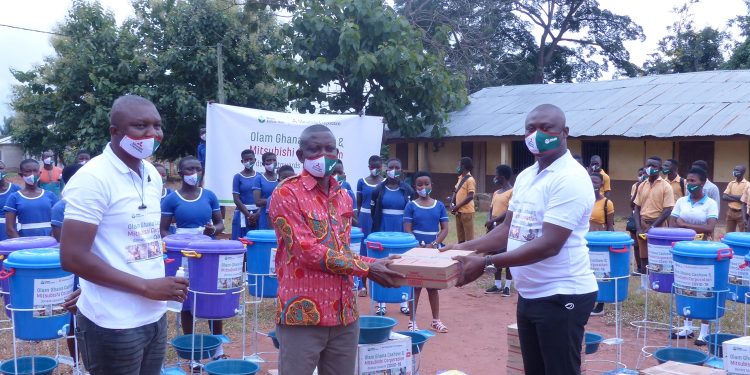 Mr. Yussif Amankwa (right), Branch Operations Manager, Olam Cashew, hands over the supplies to Mr. Opoku Donyina (middle) District Director of Education, Nkoranza North as Mr. Rowell Weroyi, Zonal Head, Cashew looks on.