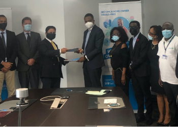 Dr. Edward Botchway and Mr. Annish Doorgapersad exchanging copies of the signed agreement while other senior members of their respective teams look on