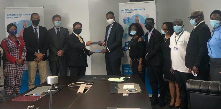Dr. Edward Botchway and Mr. Annish Doorgapersad exchanging copies of the signed agreement while other senior members of their respective teams look on