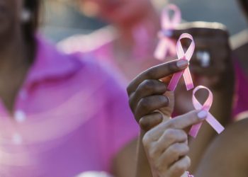 Cropped group of multi-ethnic teenage girls and young women holding breast cancer awareness ribbons in their hands, and wearing pink shirts.  Credit: Getty Images/iStockphoto