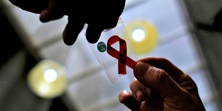 A nurse (L) hands out a red ribbon to a woman, to mark World Aids Day, at the entrance of Emilio Ribas Hospital, in Sao Paulo December 1, 2014. The world has finally reached "the beginning of the end" of the AIDS pandemic that has infected and killed millions in the past 30 years, according to a leading campaign group fighting HIV. United Nations data show that in 2013, 35 million people were living with HIV, 2.1 million people were newly infected with the virus and some 1.5 million people died of AIDS. By far the greatest part of the HIV/AIDS burden is in sub-Saharan Africa. REUTERS/Nacho Doce (BRAZIL - Tags: HEALTH SOCIETY)