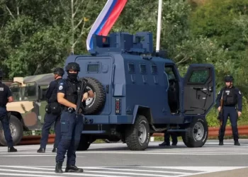 Kosovo police at the scene with troops from the US and EU states in the background