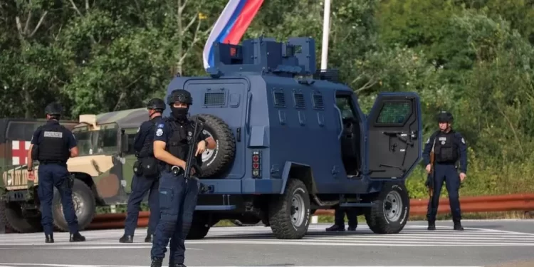 Kosovo police at the scene with troops from the US and EU states in the background