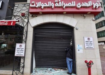 A Palestinian man inspects the damage to a money exchange shop in Ramallah