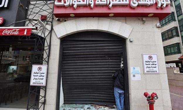 A Palestinian man inspects the damage to a money exchange shop in Ramallah